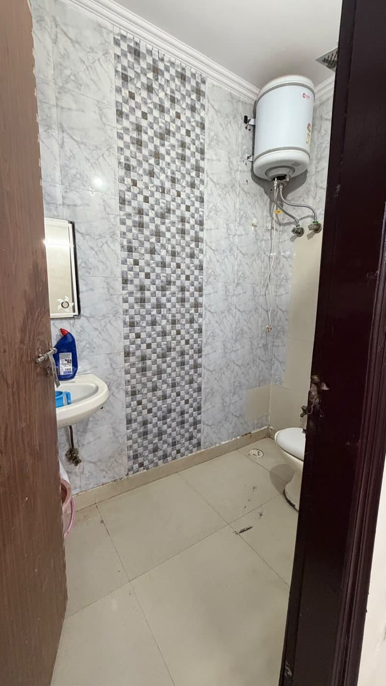 Clean tiled attached bathroom with a geyser and washbasin