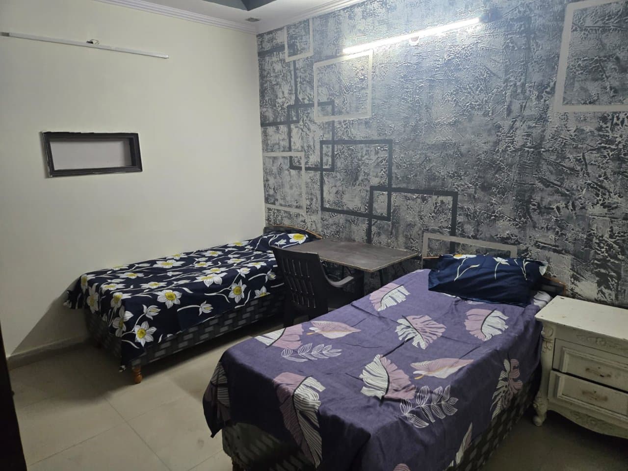 Furnished double-sharing room at Manvi Homes Stay PG with beds, side tables and study space